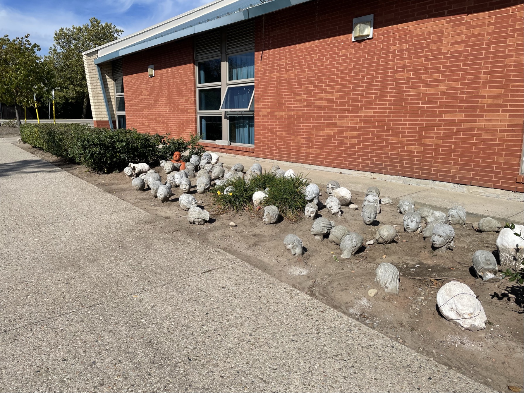 Image taken for the spatial workshop 1 taken outside the AS building. It appears to have sculpted faces made of clay planted on this mount of dirt.